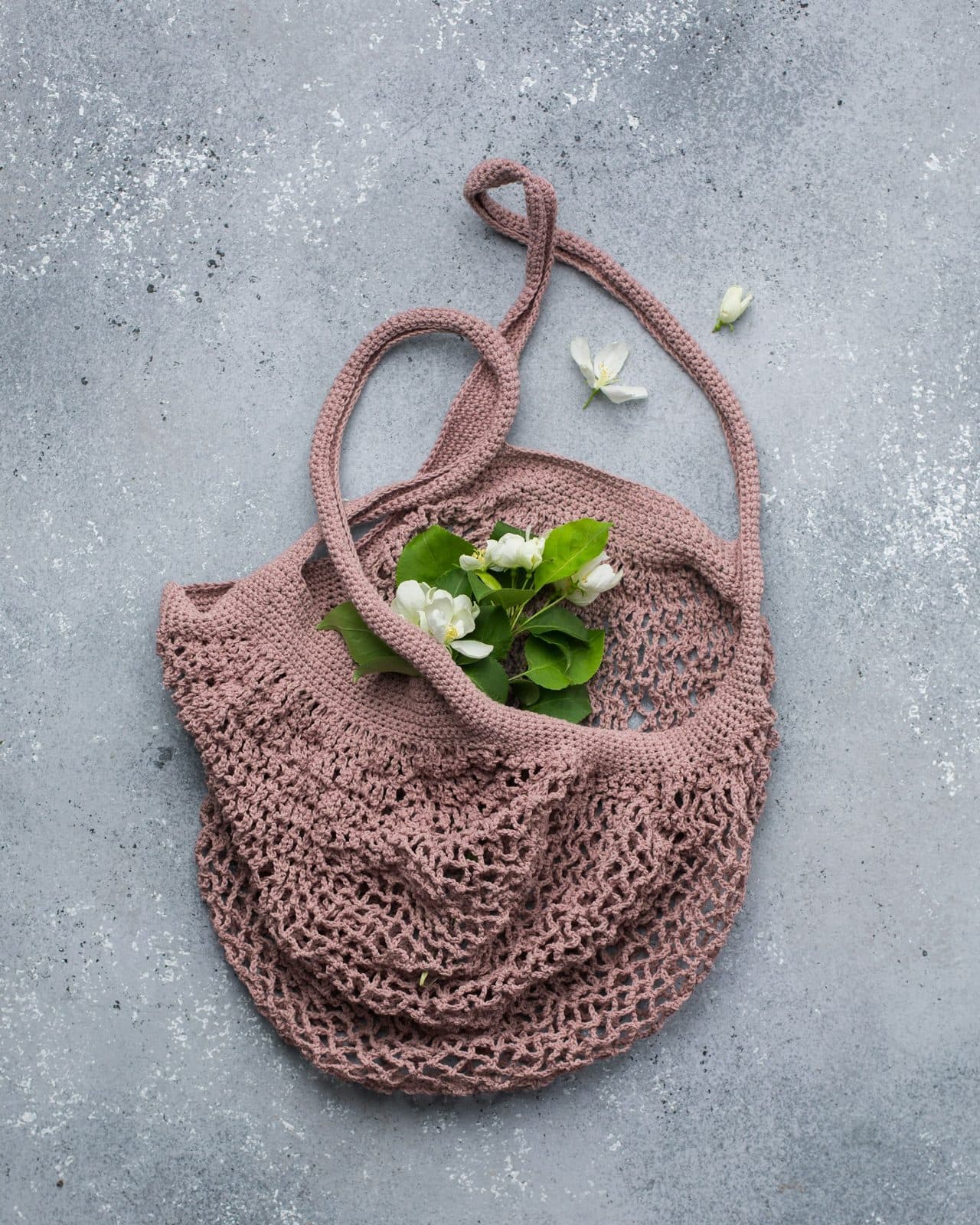Bolsa de malla de ganchillo rosa palo con flores blancas