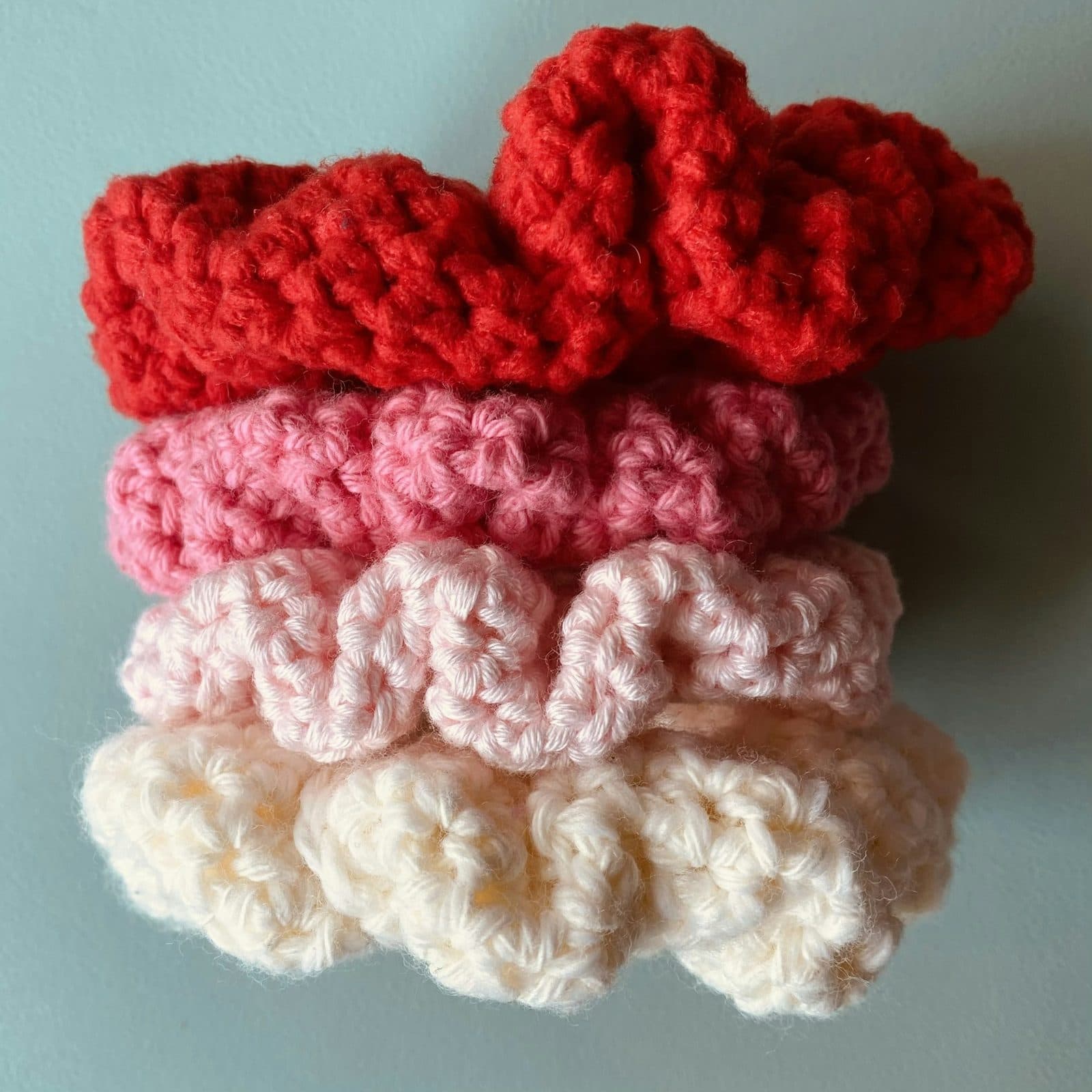 Scrunchies de ganchillo apilados en degradado de rojo a crudo